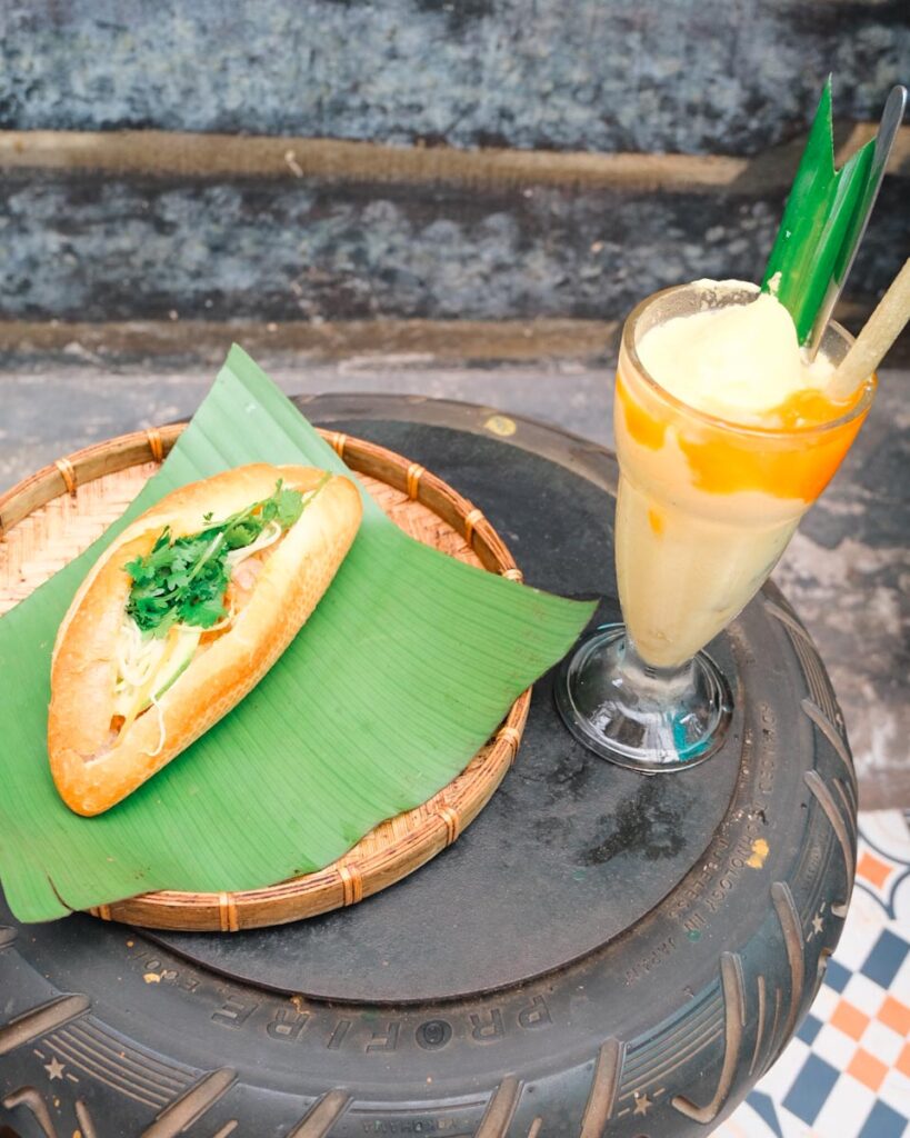Best cafes with food in Vietnam at Hidden Gem Cafe. This is a bahn mi sandwich and mango smootie