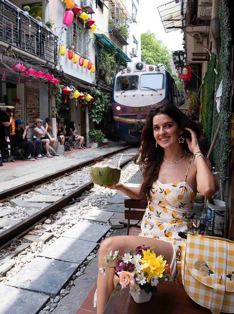 female solo traveler sitting at a cafe on hanoi train street in vietna,
