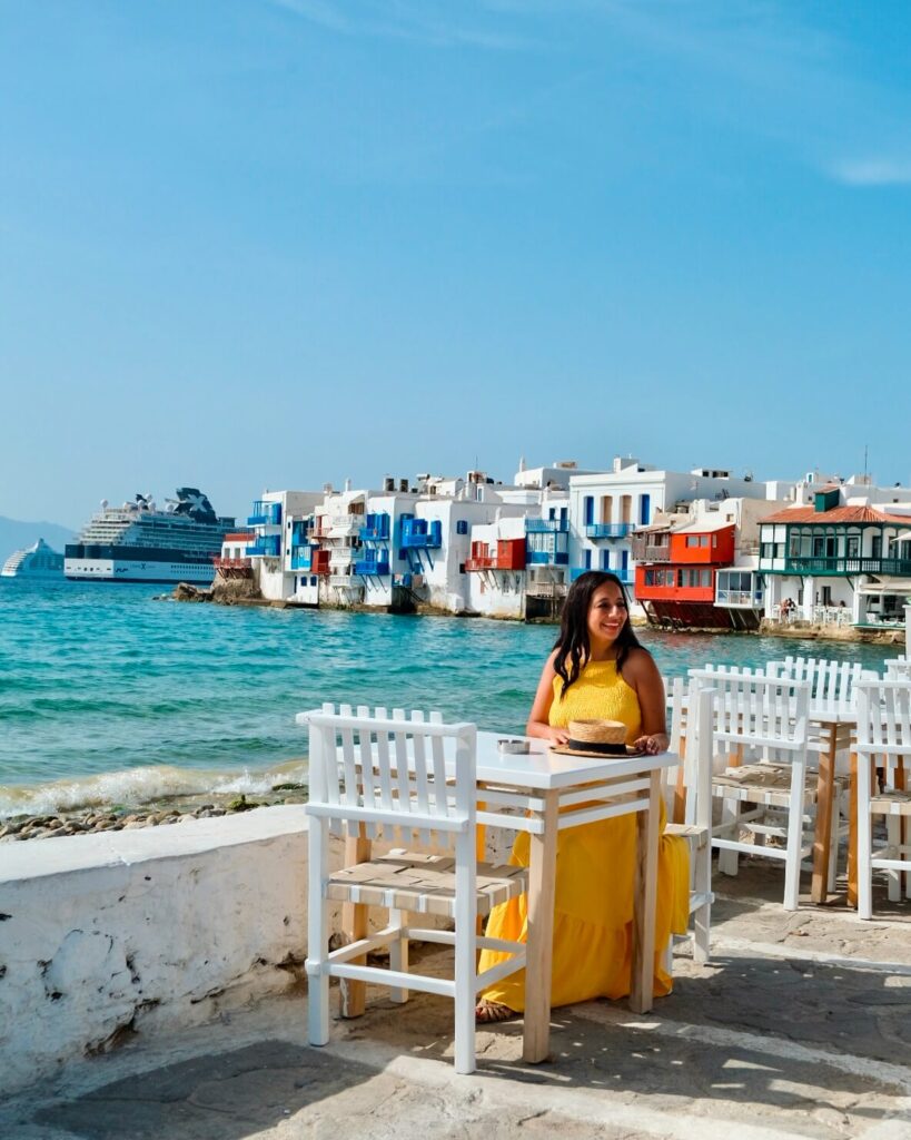female sitting at a white table in little venice mykonos at nice n easy restaurant 