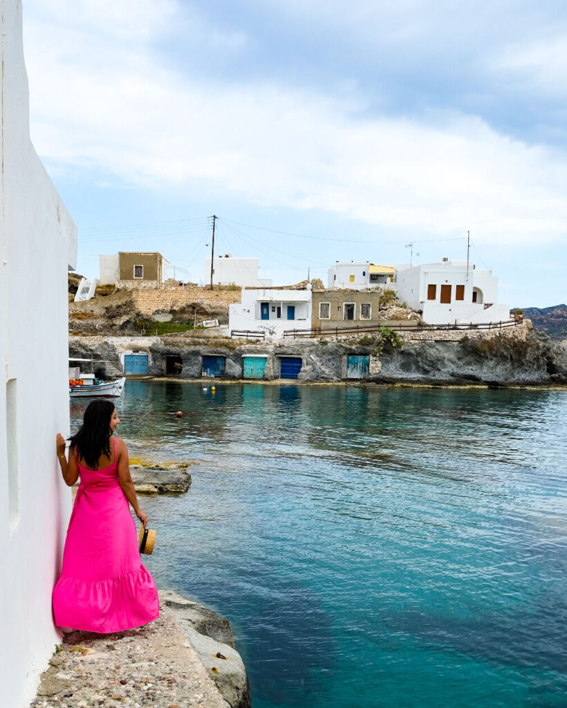 female in pink standng in front of a view of Rema beach in Kimolos