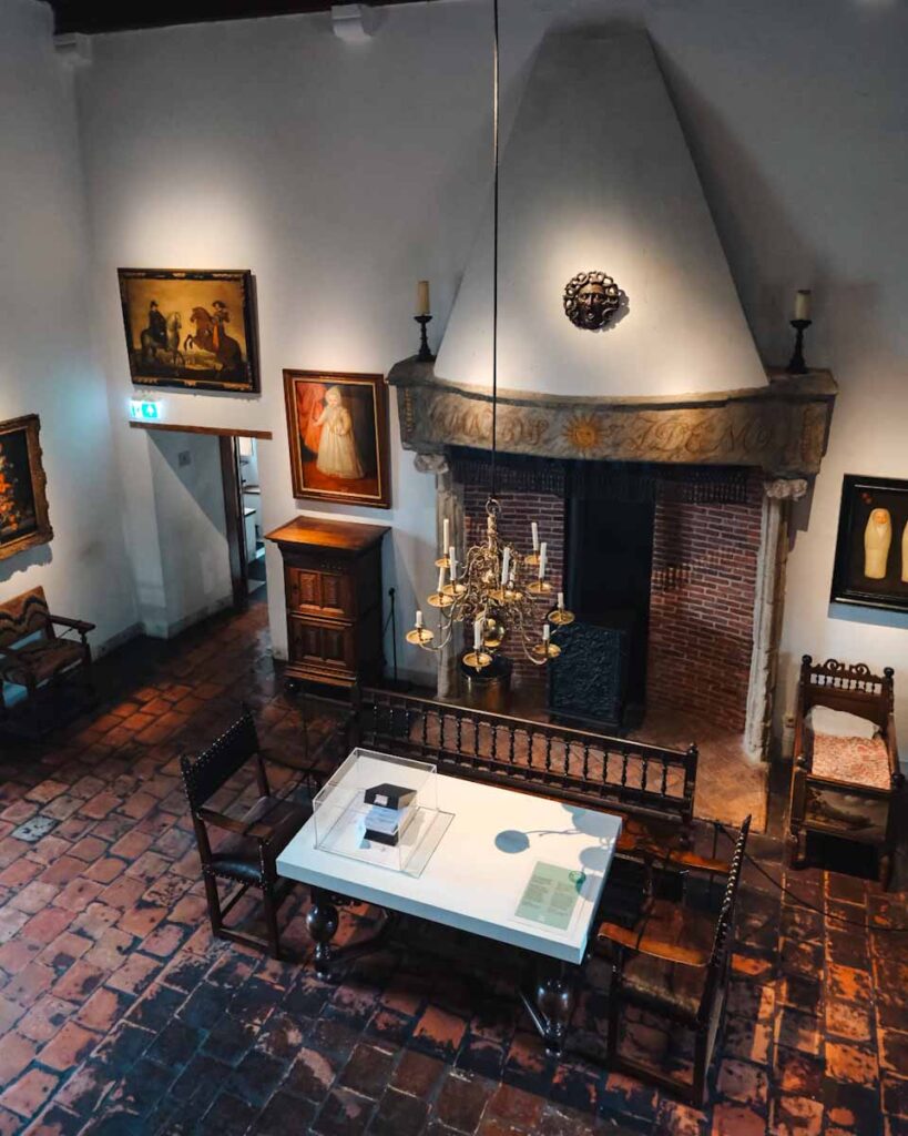 the interior of muiden castle a table and artwork is hanging on the walls.