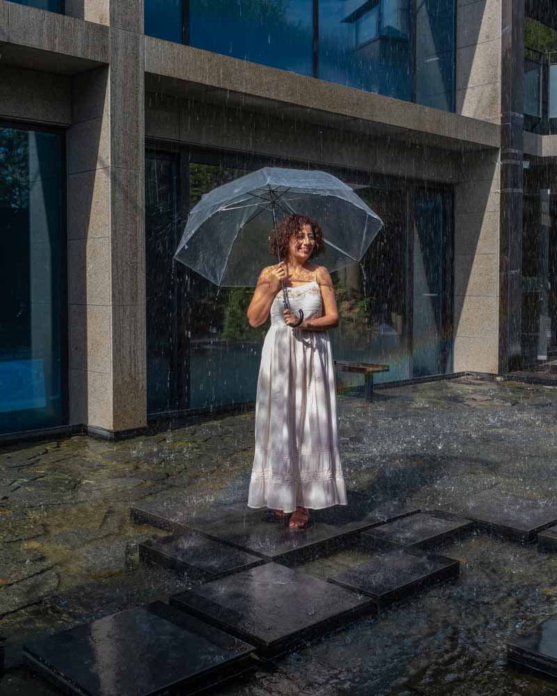 woman with an umbrella at a cafe that rains in seoul called the rain report cafe